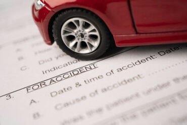 A red toy car atop an insurance claims form